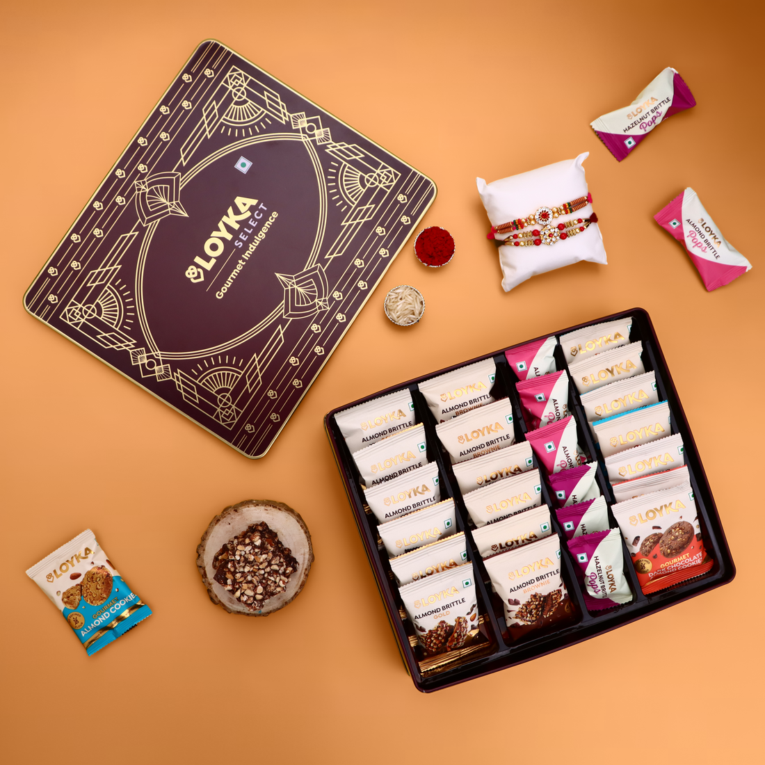 Loyka Select Regal Tin (Reusable) With 2 Rakhi, Roli, Chawal & Card – A Luxurious Gifting Delight with 5 Almond Brittle Gold, 5 Brownie, 8 Pops, 6 Cookies & Rich Dark Chocolate Almond Treats